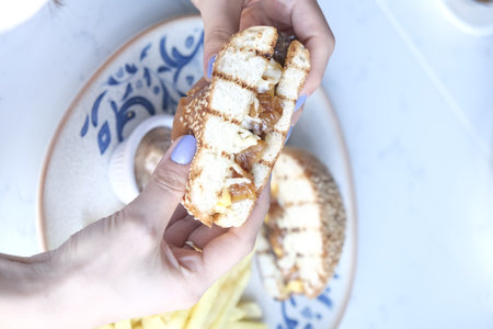 Hands holding a sandwich with cheese on a plate.の写真素材