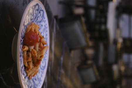 Pasta with tomato sauce in a ceramic plate on the kitchen tableの写真素材