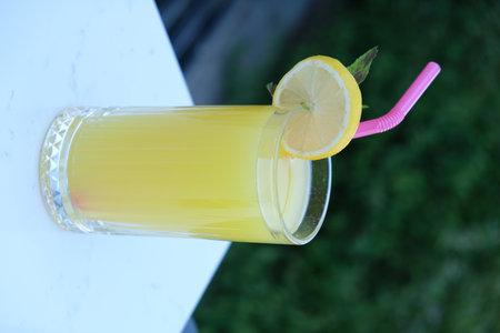 A glass of juice with a straw and a slice of lemon.の写真素材