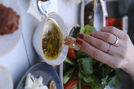 Close up of a woman's hand dipping bread in olive oil.