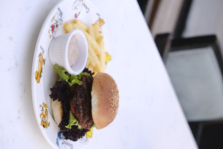 Hamburger and french fries on a white plate on the tableの写真素材