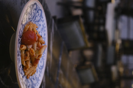 Ceramic plate of pasta with tomato and cheese on the tableの写真素材