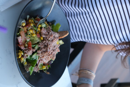 Tuna salad with mixed vegetables in black bowl on the table.の写真素材