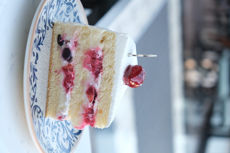 A piece of cake with raspberries and cherries on top