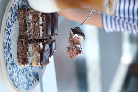 Close up of a woman's hand sprinkling chocolate on a cakeの写真素材
