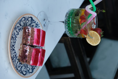 Strawberry cake in a glass with a straw on the tableの写真素材