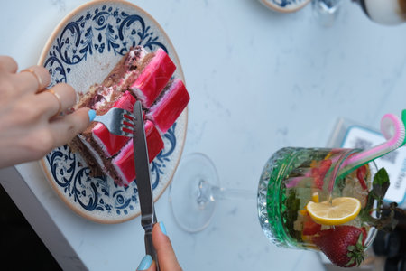 Close up of female hands cutting piece of cake with knife and forkの写真素材