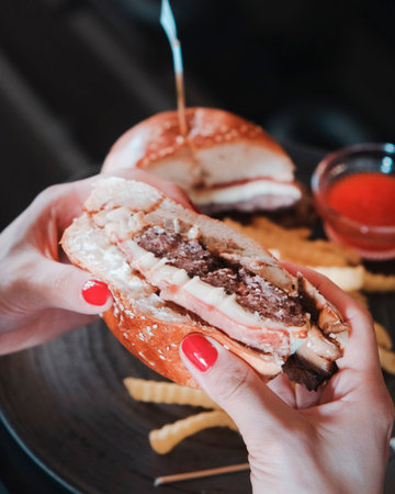 Hands of woman eating hamburger with french friesの写真素材
