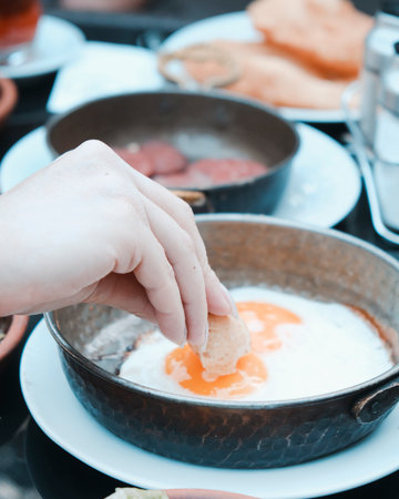 Fried eggs on a frying pan with a woman's hand.の写真素材