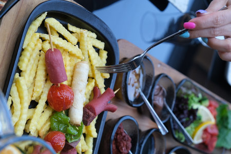 Fried sausage with french fries and vegetables on the table in a restaurantの写真素材