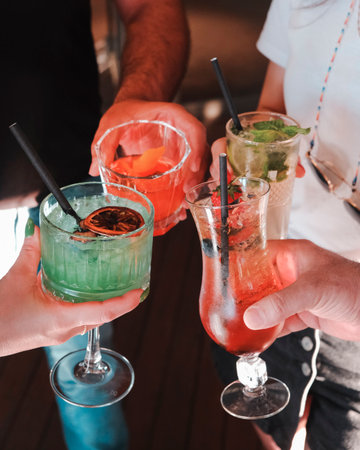 Close-up of hands of barman and woman holding glasses with cocktailsの写真素材
