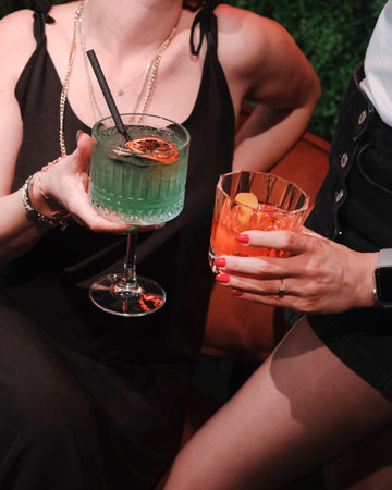 Two female friends toasting with cocktails in a bar, close-up
