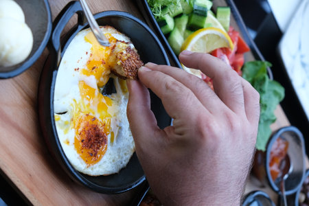 Close up of a man's hand taking a fried egg from a breakfast tray.の写真素材