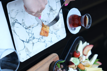 Woman's hand is holding a knife and fork with a slice of bread