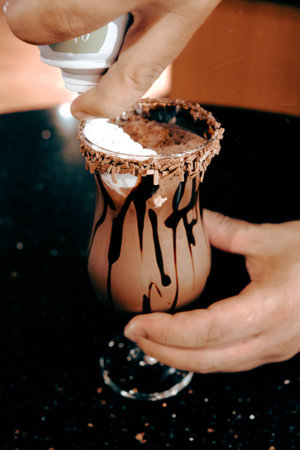 A person preparing a chocolate drink in a glassの写真素材