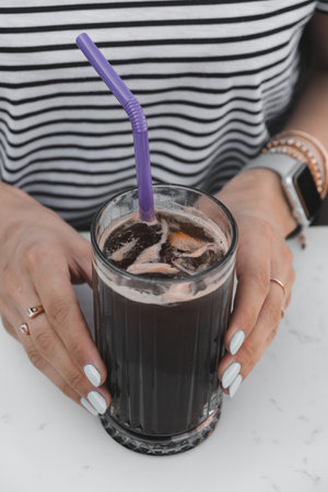 A glass of cold beverage with a straw on the tableの写真素材