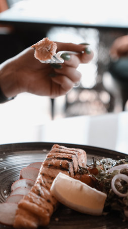 Fried sea bream fish on white plate with onion, garden rocket and lemon slicesの写真素材