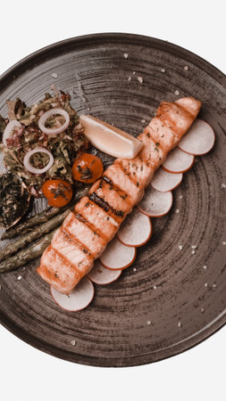 Fried sea bream fish on white plate with onion, garden rocket and lemon slicesの写真素材