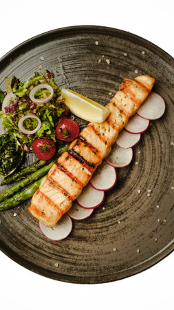 Grilled fish on plate with vegetables and lemon slicesの写真素材