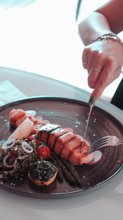 Fried sea bream fish on white plate with onion, garden rocket and lemon slicesの写真素材