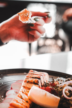 Fried sea bream fish on white plate with onion, garden rocket and lemon slicesの写真素材