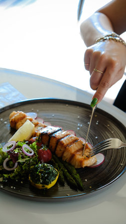 Fried sea bream fish on white plate with onion, garden rocket and lemon slicesの写真素材