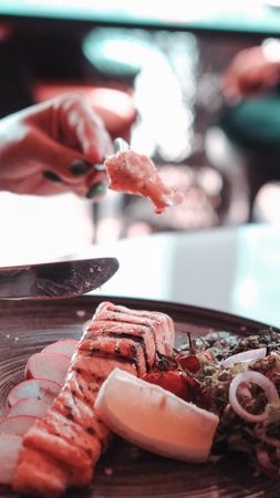 Fried sea bream fish on white plate with onion, garden rocket and lemon slicesの写真素材