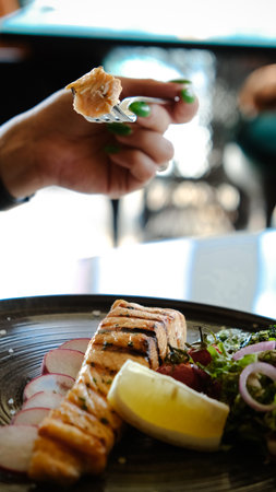 Fried sea bream fish on white plate with onion, garden rocket and lemon slicesの写真素材