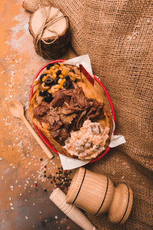 Baked kumpir potato stuffed with the cheese, sausage, olives, peppers and cornの写真素材