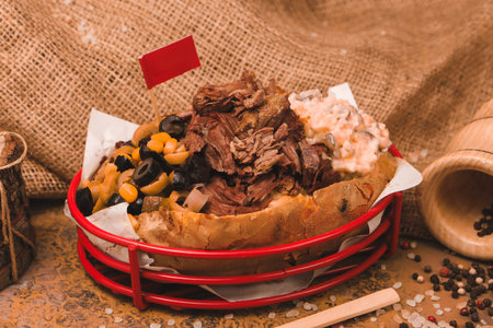 Baked kumpir potato stuffed with cheese, sausage, olives, peppers and cornの写真素材