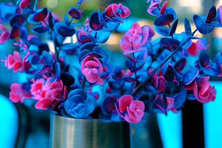 Blue and pink artificial flowers in a vase on a blue backgroundの写真素材