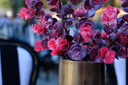 Beautiful purple flowers in a vase on a table in a cafeの写真素材