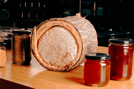Honeycomb with honey in a jar on a wooden table.