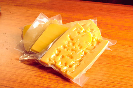 Slices of cheese in a plastic bag on a wooden table