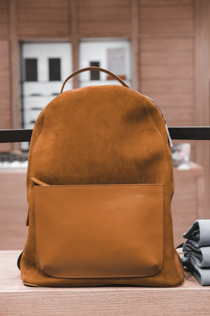 Close up of a brown leather backpack on a wooden benchの写真素材