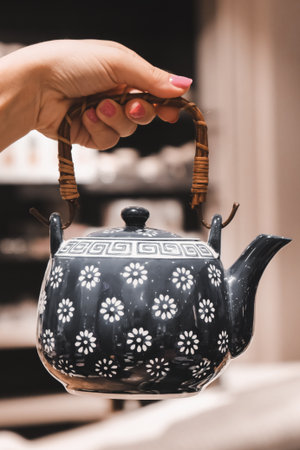 teapot in the hand of a woman with a red manicureの写真素材