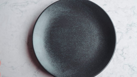 Top view of empty black plate on white marble table with copy space