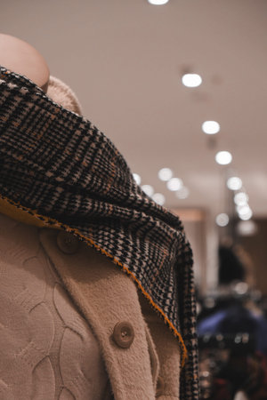 Female mannequin wearing a coat and scarf in a fashion store.