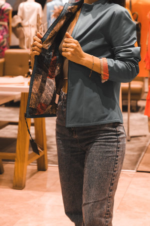 A woman in a blue blouse and jeans is shopping in the store