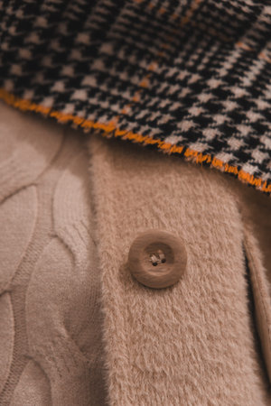 Closeup of a button on a beige woolen coat.