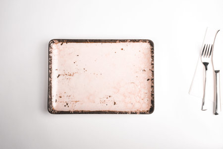 Empty ceramic plate and cutlery on white background, top view