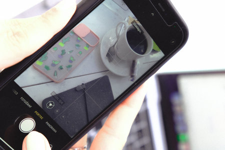 Smartphone in hand and a cup of coffee on the table.