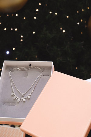 Pearl necklace in a gift box on the background of a Christmas tree