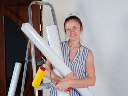 A happy woman holds rolls of new Wallpaper in her hands. Repairs in the apartment. Wallpapering.