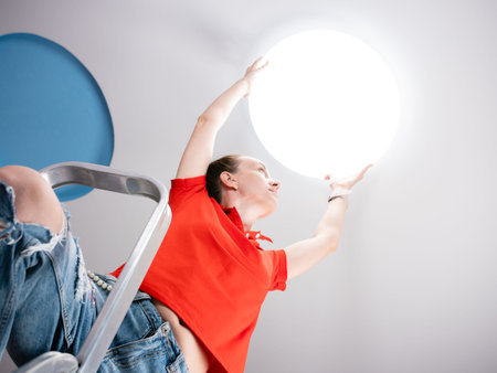 A woman in a childrens room sets a ceiling lamp.