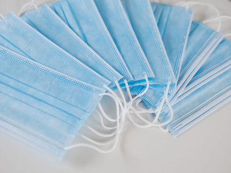 A lot of face mask or surgical mask lays on a white table. Coronavirus COVID-19 diseases prevention...