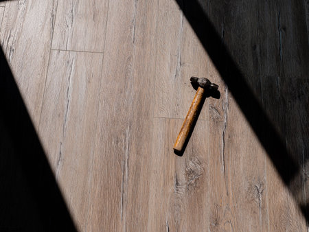 The hammer is lying on the laminate floor in a strip of sunlight from the window.