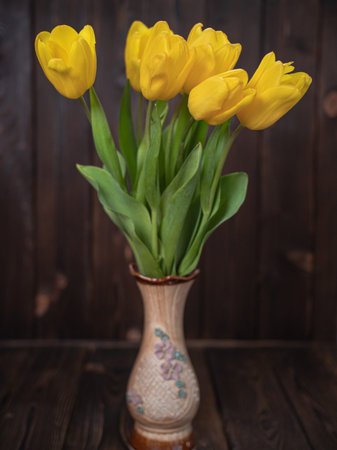Yellow tulips in a vase on a wooden rustic table. Spring holidays concept background and mothers day.の写真素材