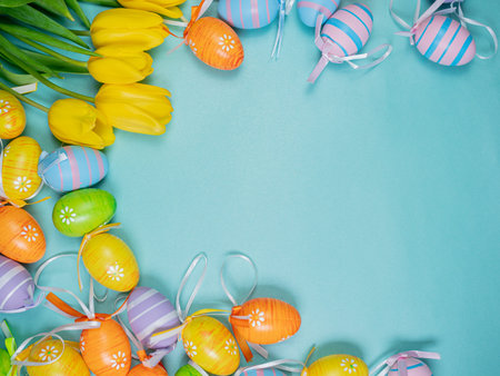 Bouquet of spring yellow tulips and colorful easter eggs on a blue background