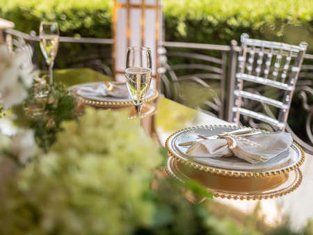 Glasses of champagne and a sumptuously served table in a summer restaurant waiting for dear guests.の写真素材
